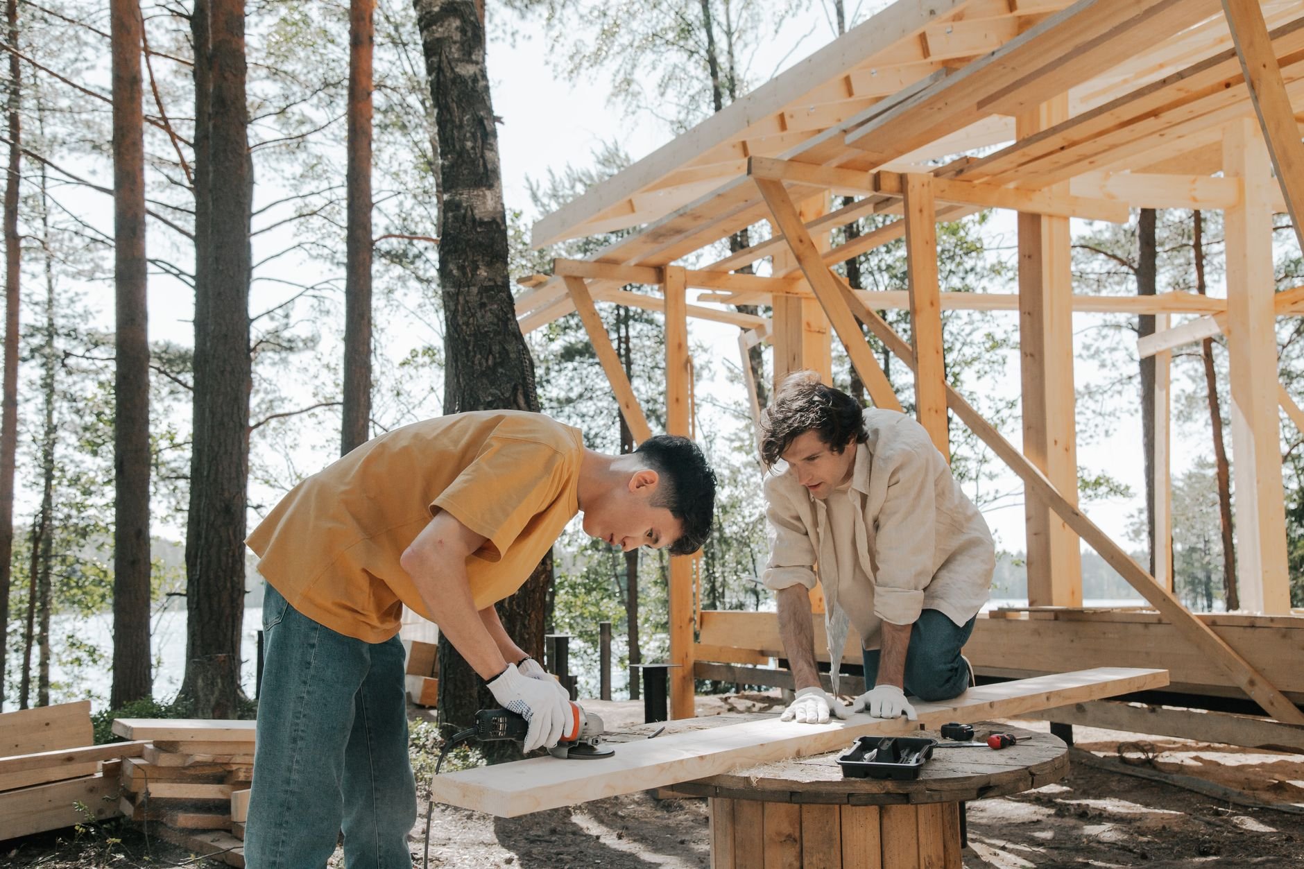 Two carpenters constructing a wooden frame structure outdoors
